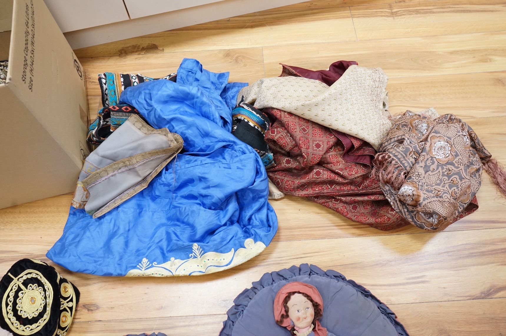 A quantity of mostly 20th century Middle Eastern and Indian woven and printed textiles and a peacock feather fan (2 boxes).